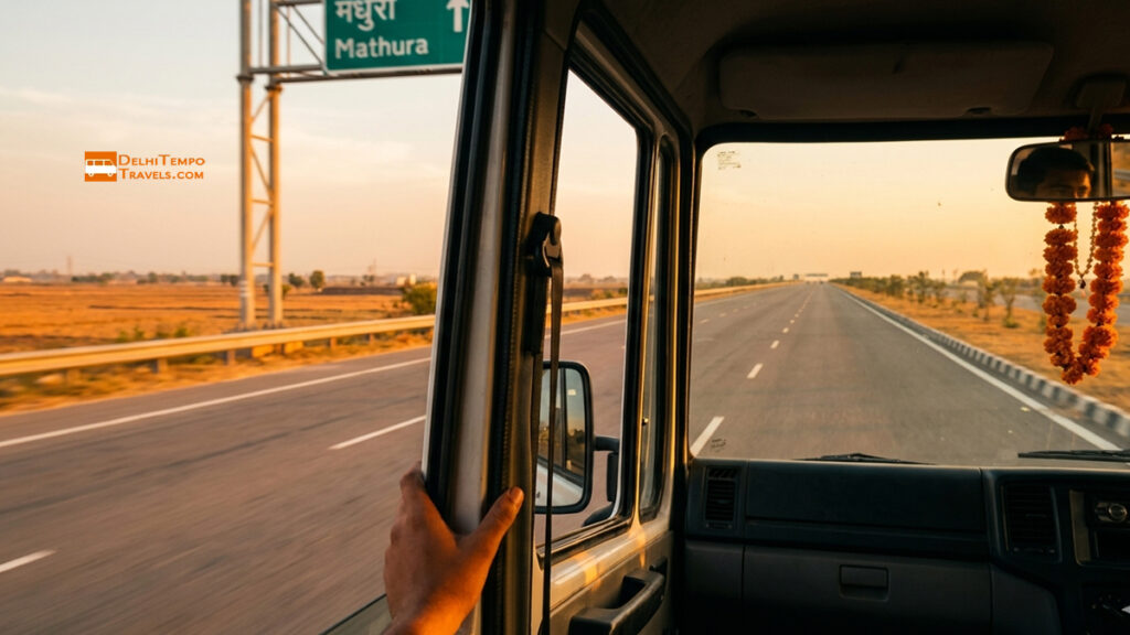 Wide cinematic photograph shot from just inside the open sliding door of a moving tempo traveller on the Yamuna Expressway at golden hour
